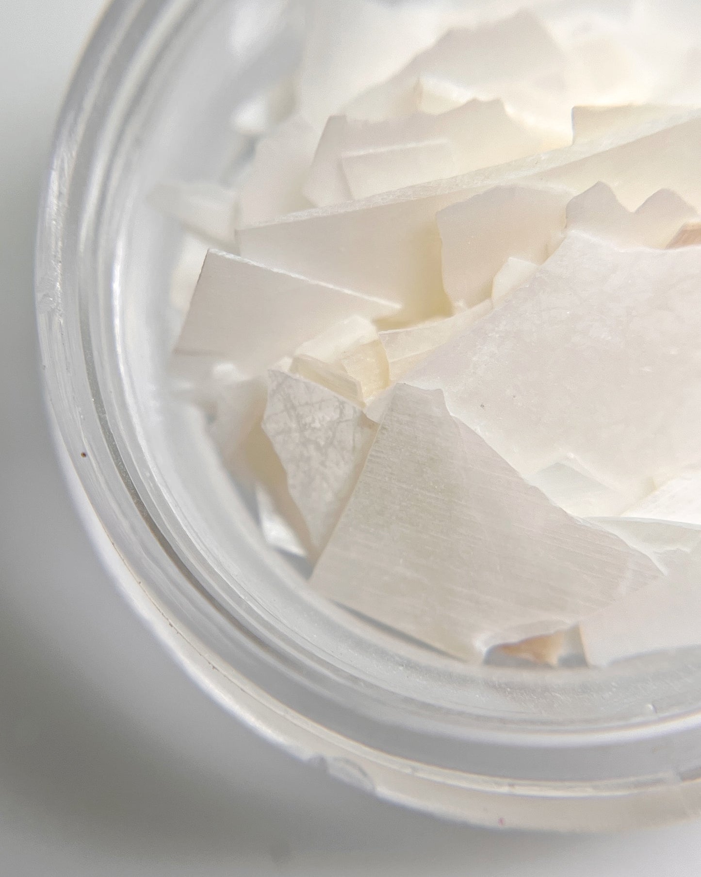 Close-up of white shell flakes in a clear container on a light gray background