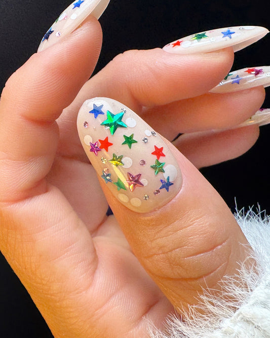 Close-up of a hand with colorful star nail art on a black background