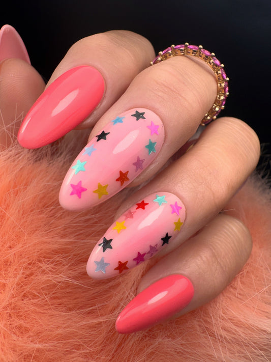 Nail art with pink base and colorful star designs on a orange fuzzy background