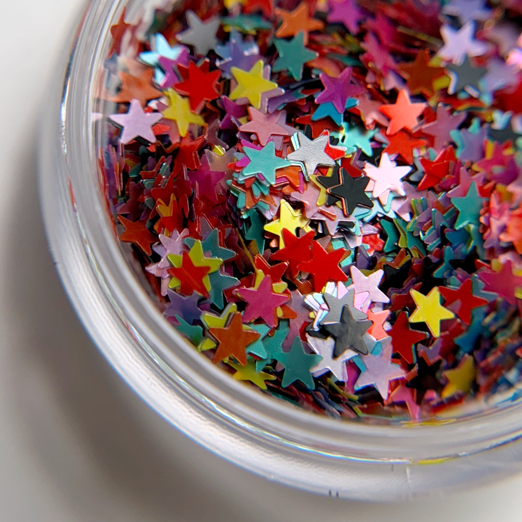 A clear container filled with multicolored star-shaped glitter pieces.