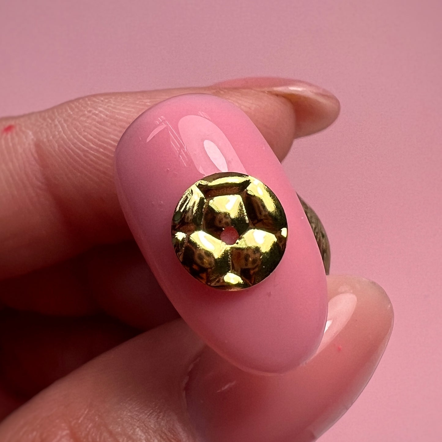 Pink nail with a gold decorative element on a pink background