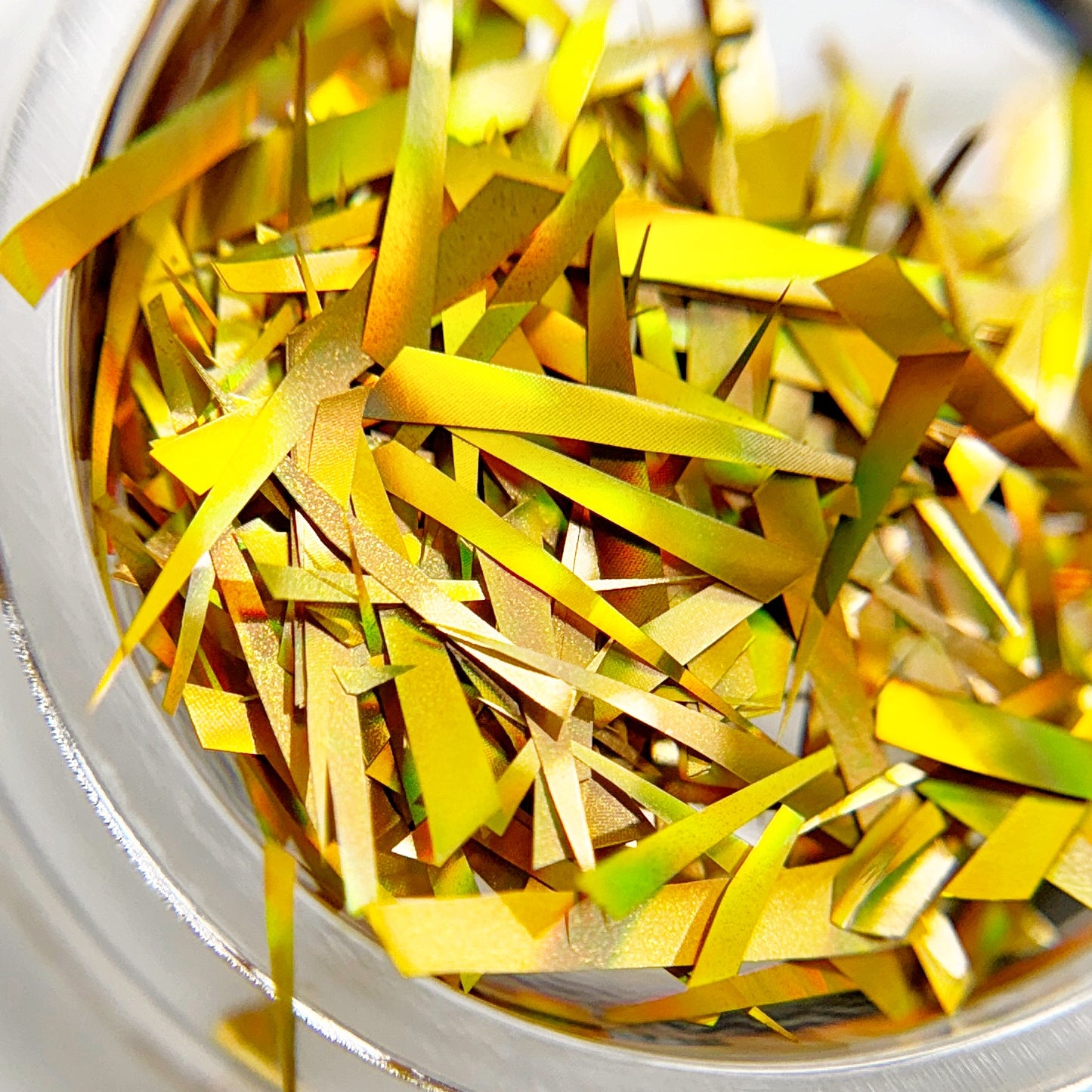 Close-up of a container filled with gold holographic foil slices in transparent jar