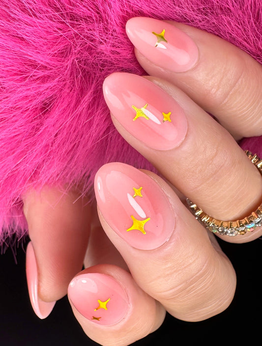 Nails with pink polish and gold star designs against a pink fur background