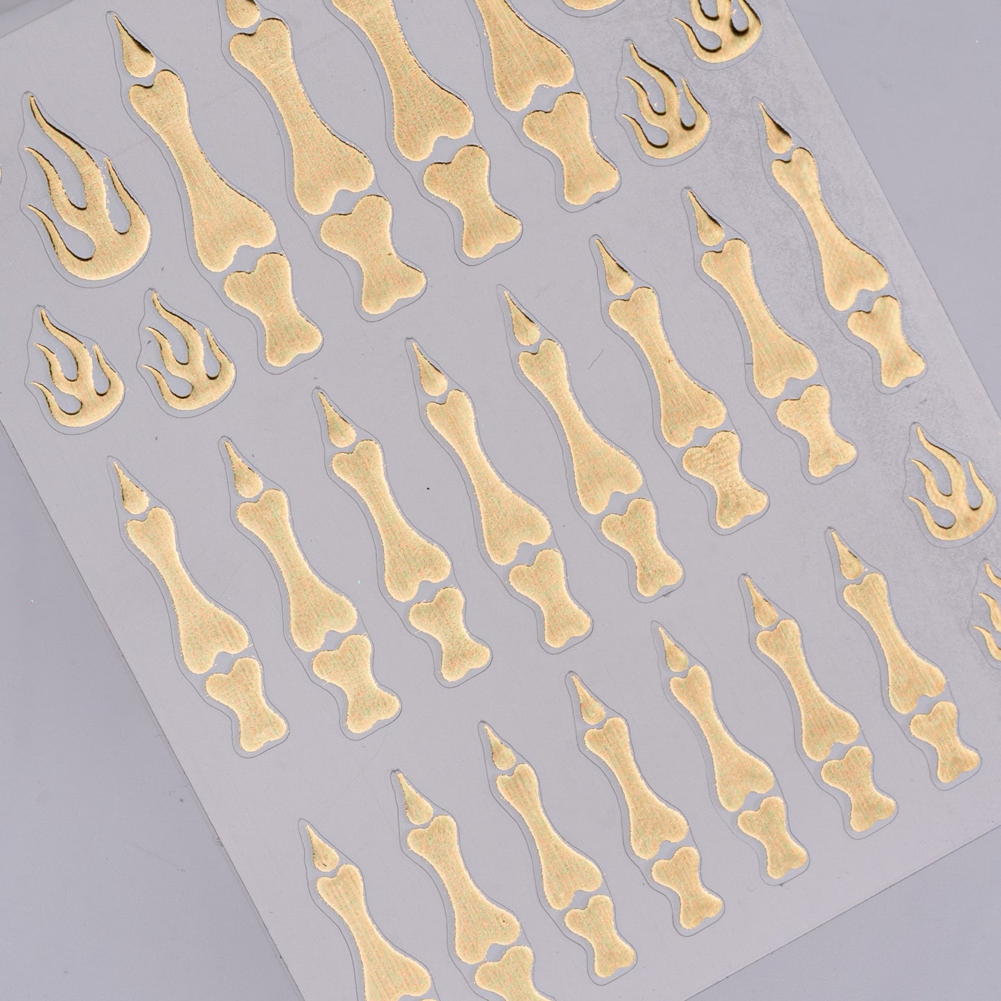 Sheet of gold bone and claw-shaped stickers on a gray background