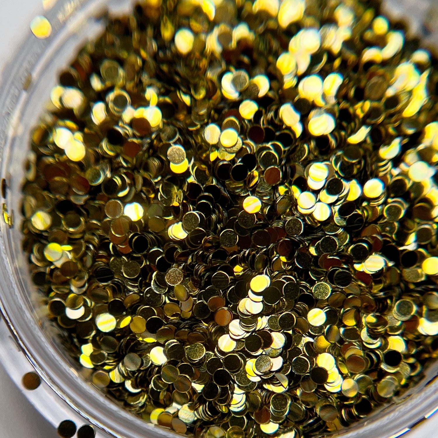 Close-up of round gold glitter in a clear container