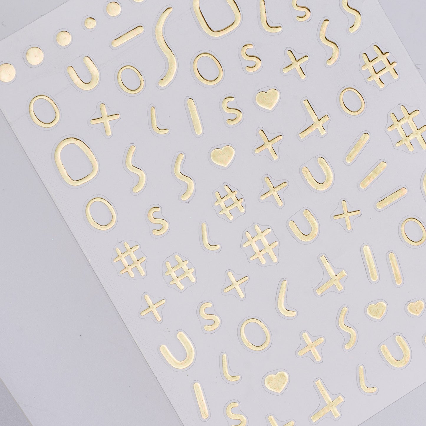 Sheet of gold letter and symbol stickers on a gray background