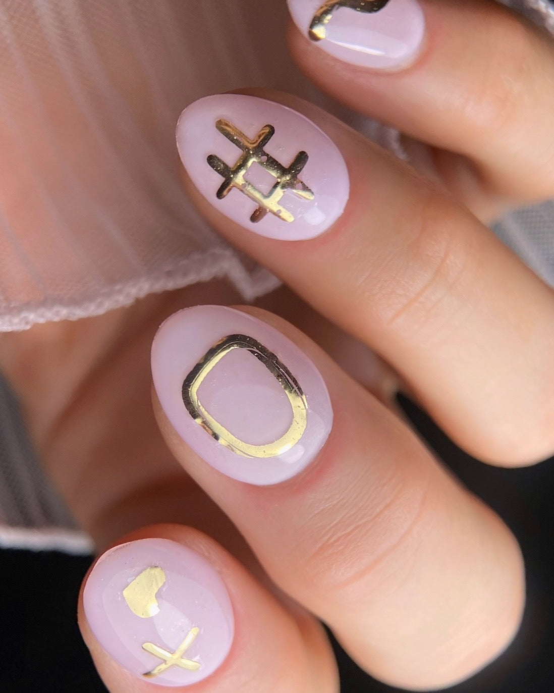 Close-up of nails with pink polish and symbol designs.