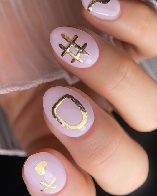 Close-up of nails with pink polish and symbol designs.