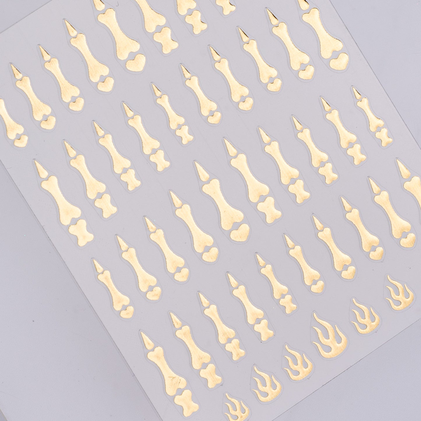Nail decal sheet featuring gold bones on a gray background