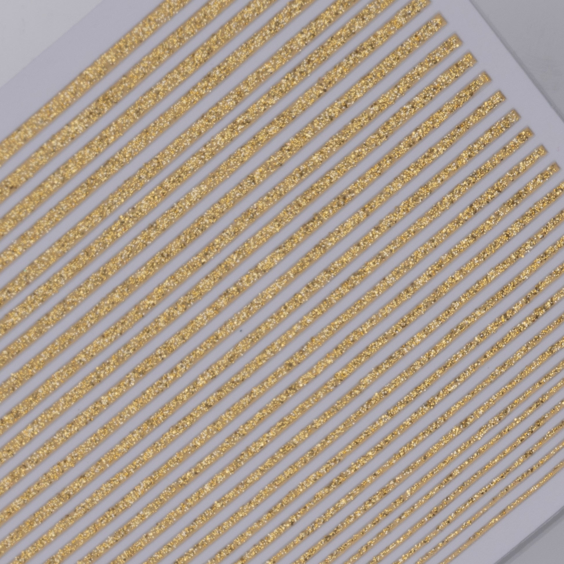 Close-up of gold glittery line nail stickers on a white background