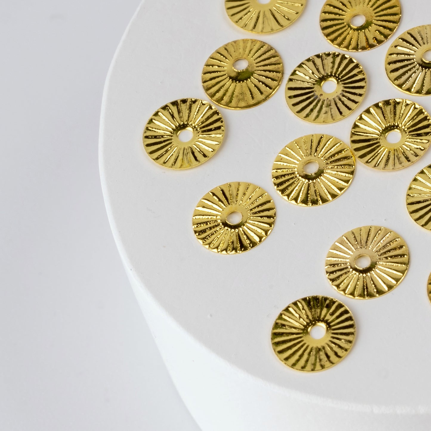 Gold nail charms on white circular base.