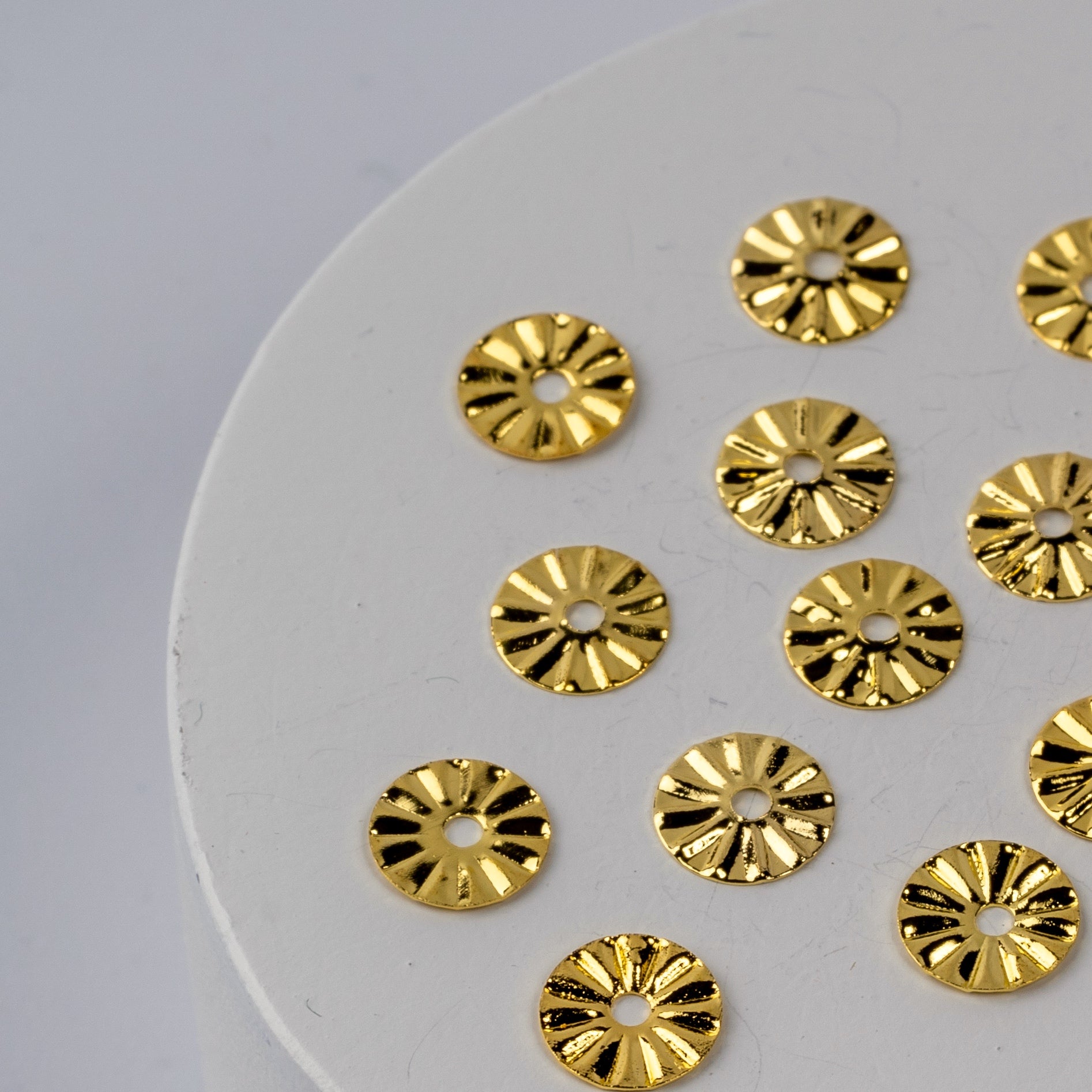 Gold nail charms on white circular base.