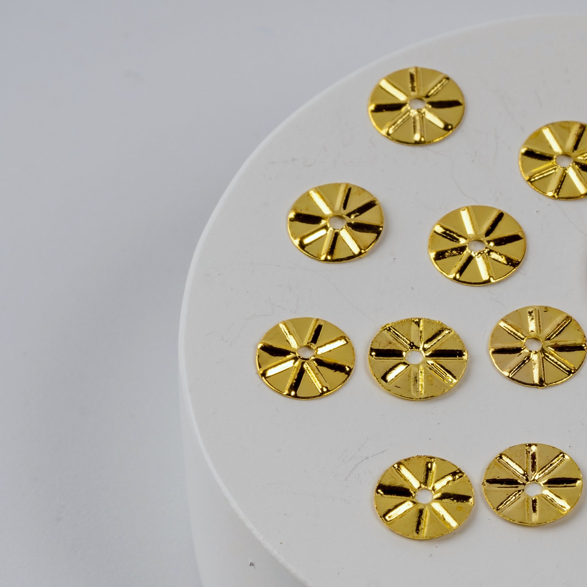 Detail view of gold nail charms on white round surface.