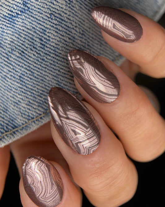 Nail art with a marbled design on a denim background