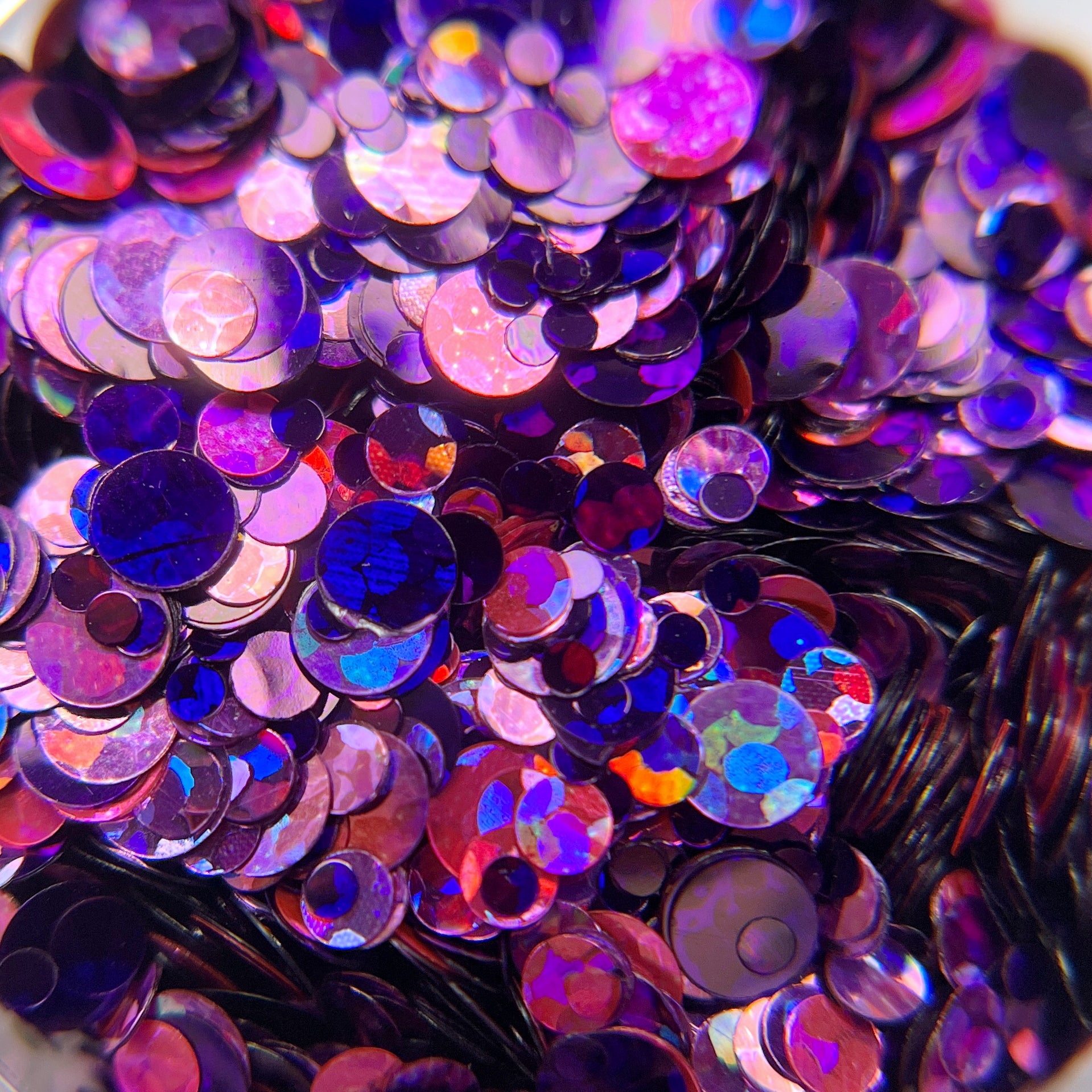 A close-up of multicolored glitter spots in purple, pink, and violet, intended for nail art.