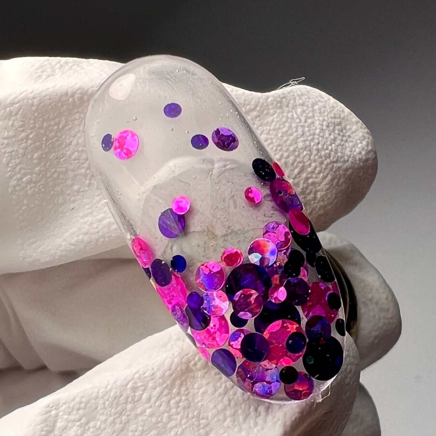 gloved hand holding decorated nail tip