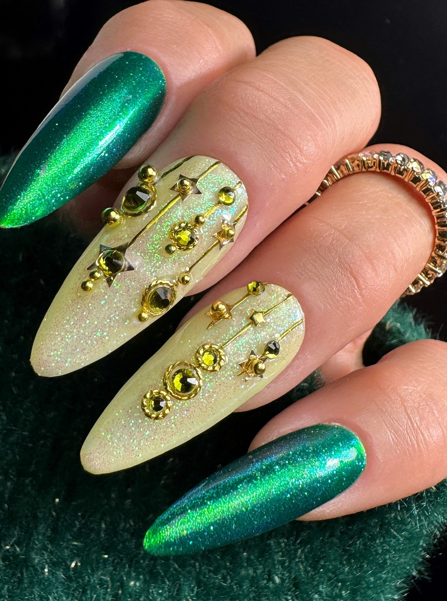 Nails with green glitter and gold decorations on a dark background