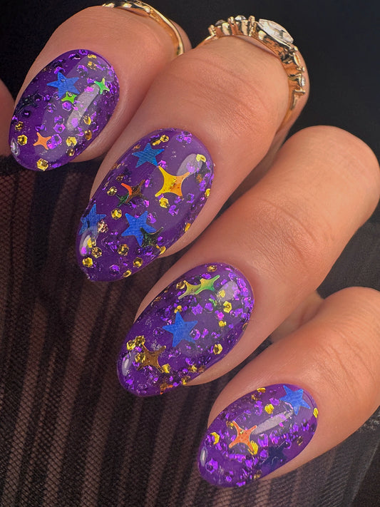 Nails with purple glitter design on a dark background