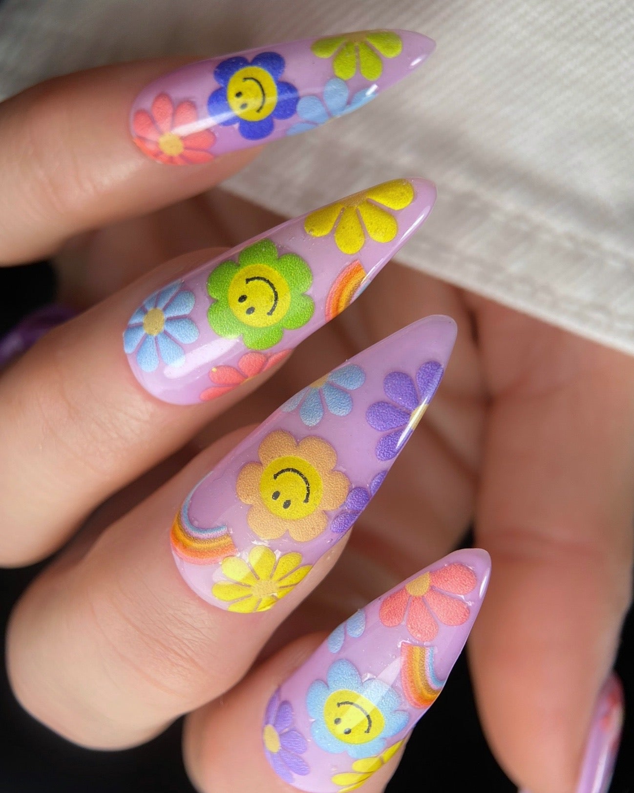 Nails with colorful floral and smiley face designs.