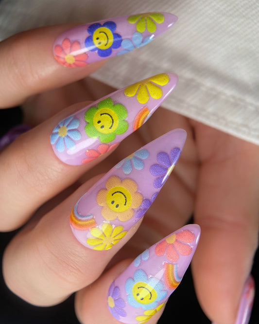 Nails with colorful floral and smiley face designs.