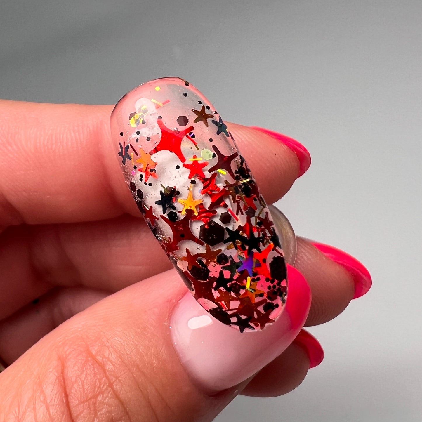 Hand holding decorated nail tip on gray background