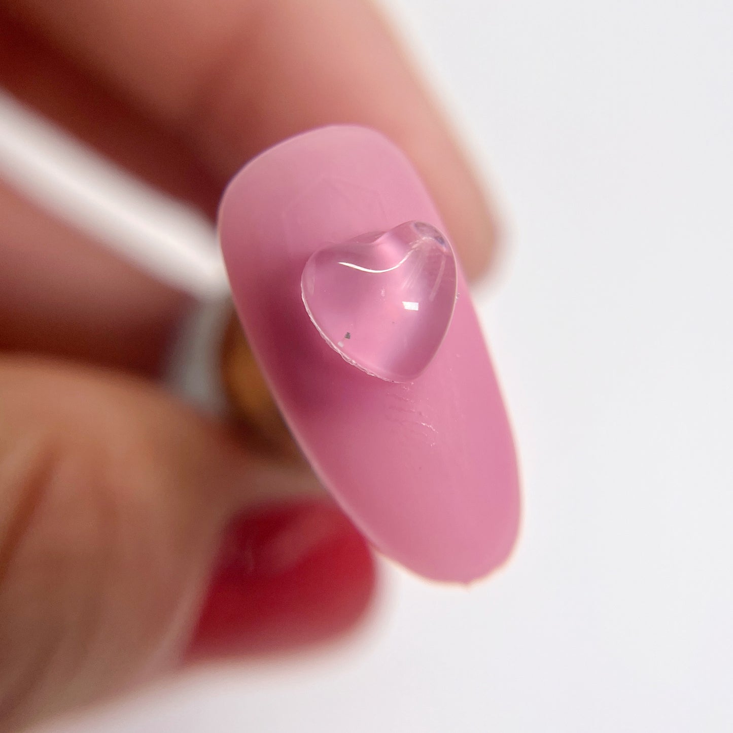 Detail view of pink nail tips with clear heart charms
