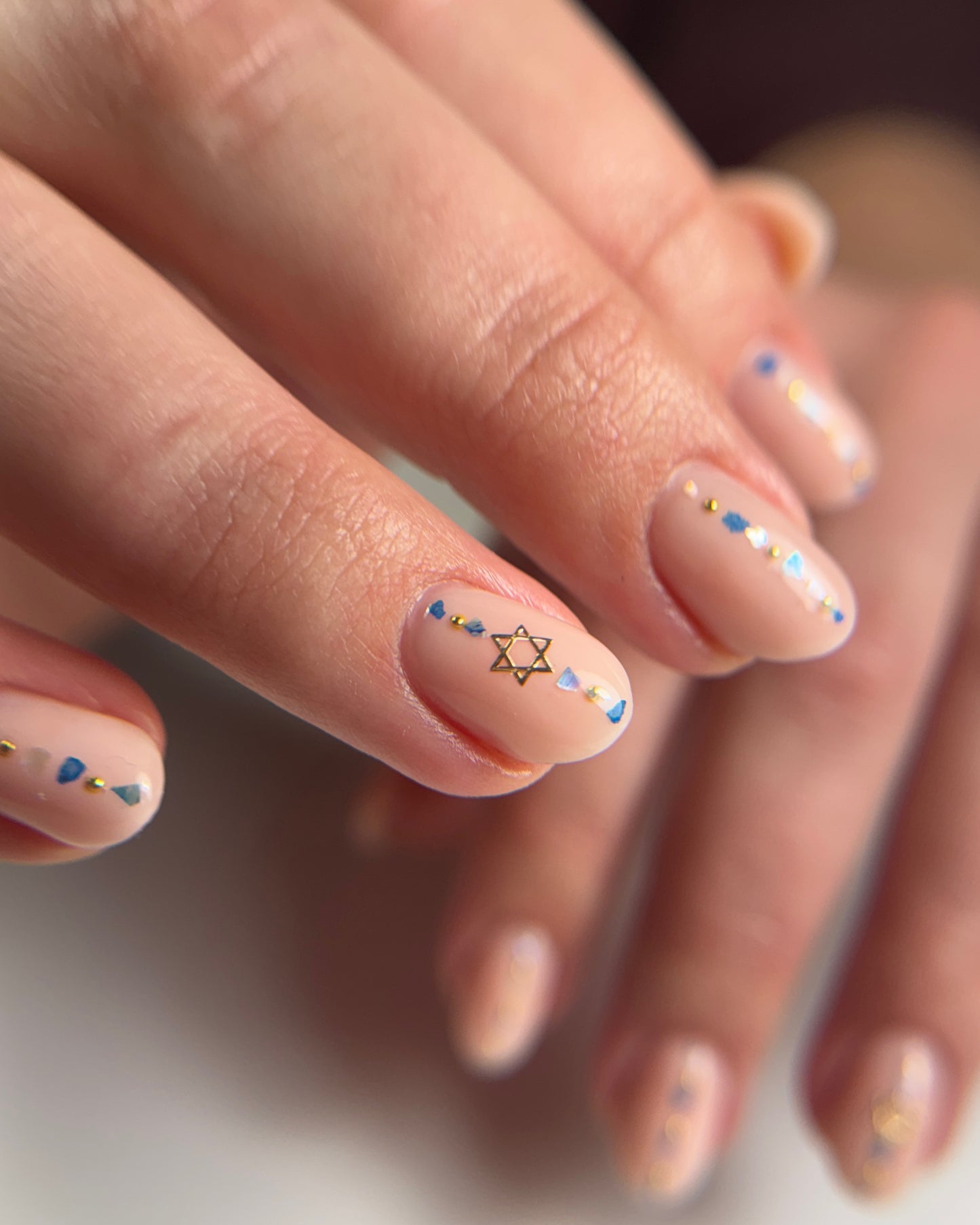 Close-up of a hand with colorful nail art on a neutral background