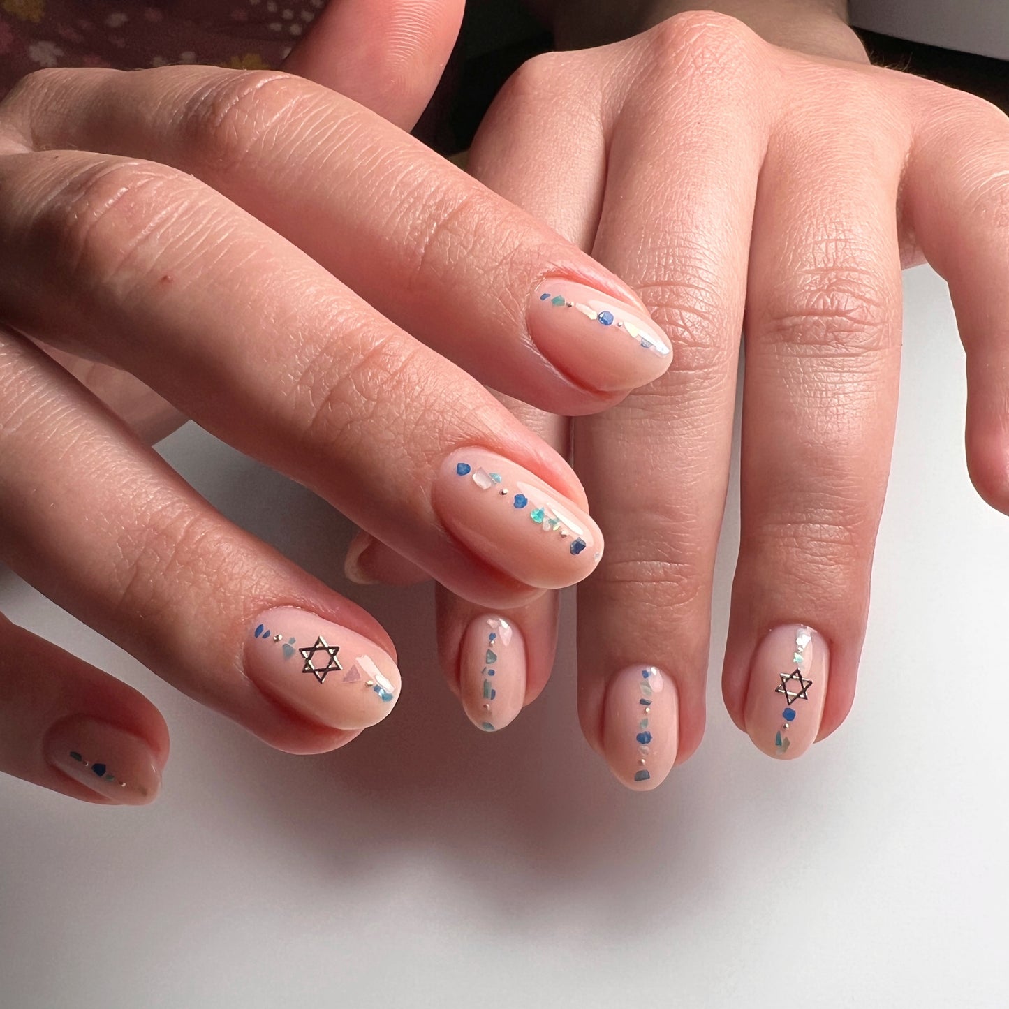 Close-up of hands with decorative nail art on a white background