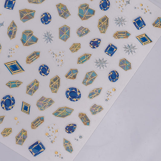Nail decal sheet with pattern of blue, gold, and silver geometric shapes on a white background