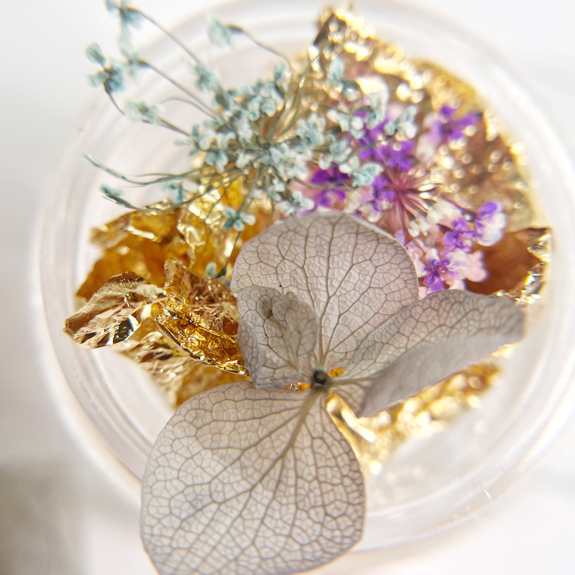 Decorative item with pressed flowers and gold leaf on a white background