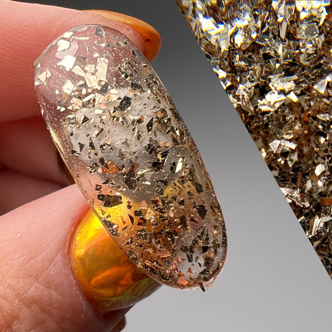 Hand holding decorated nail tip on gray background with diagonal swatch of the prpduct color. 