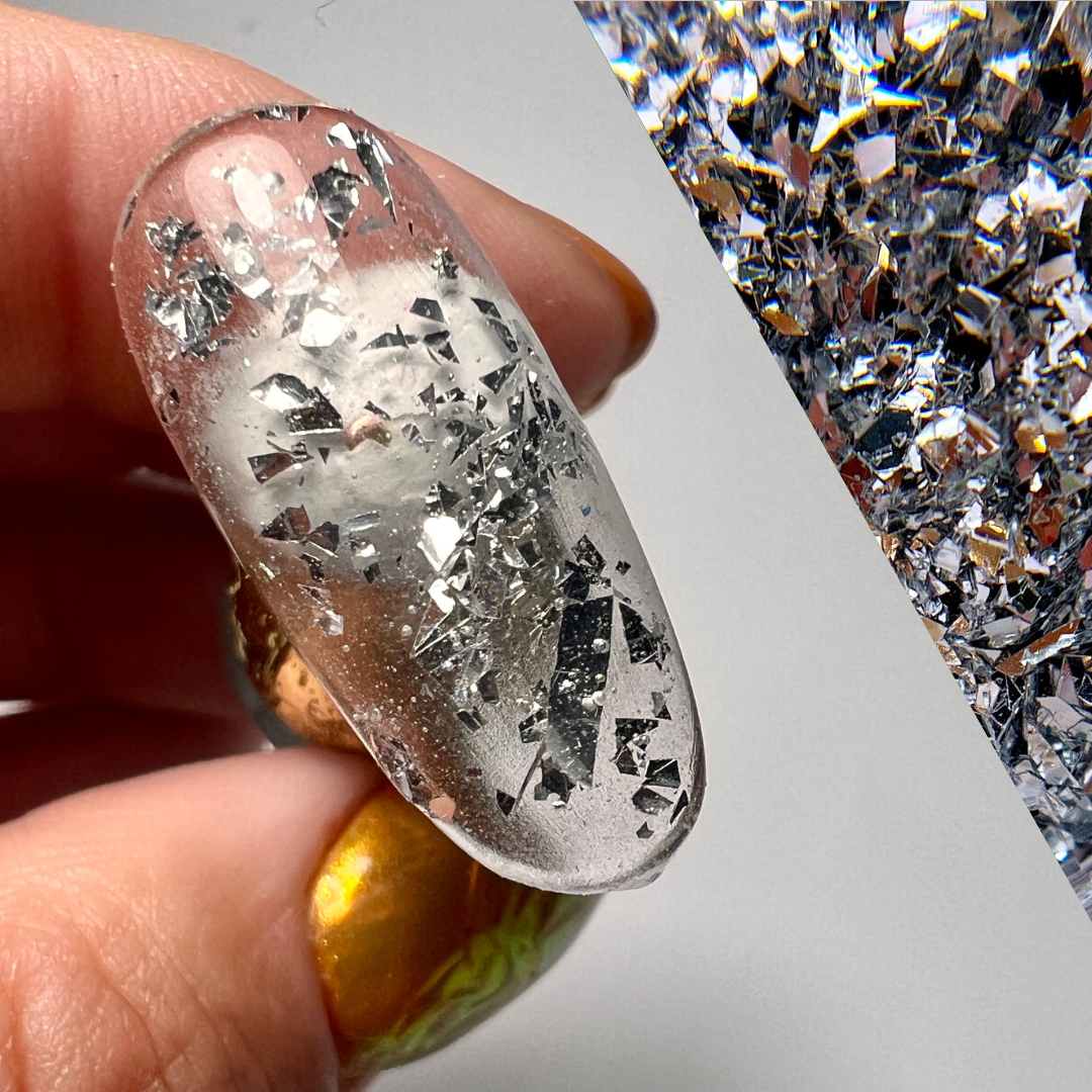 Hand holding decorated nail tip on gray background with diagonal swatch of the prpduct color. 