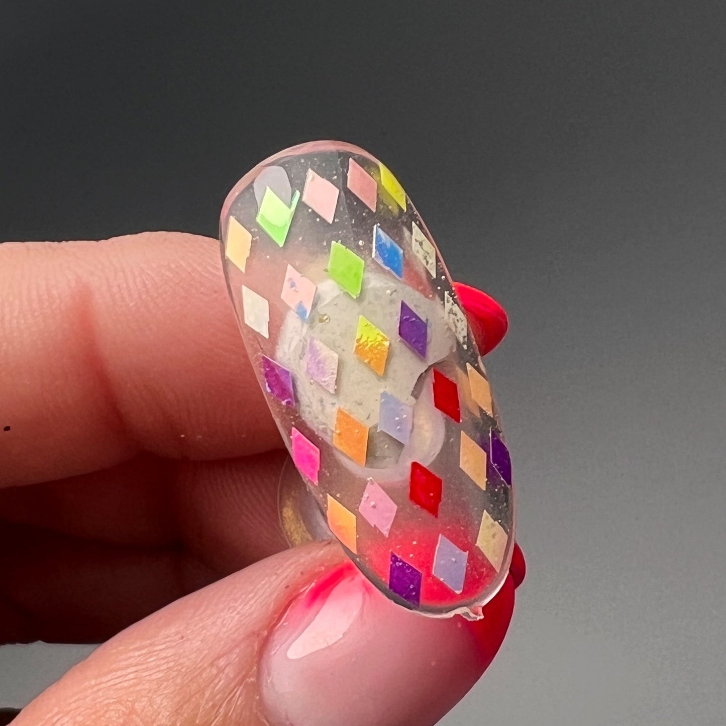 Still of hand holding decorated nail tip. 