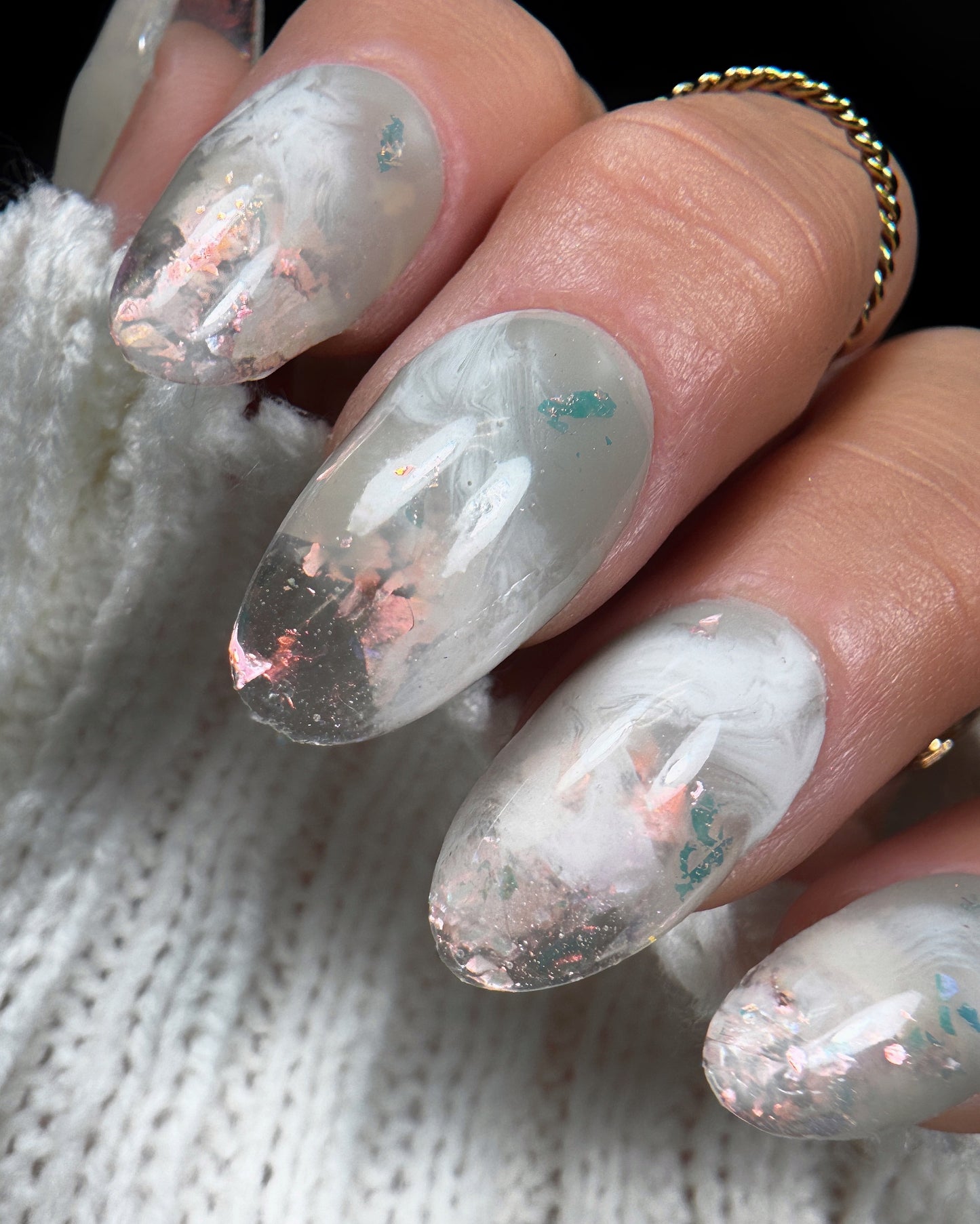 Close-up of a hand with detailed nail art on a textured white background