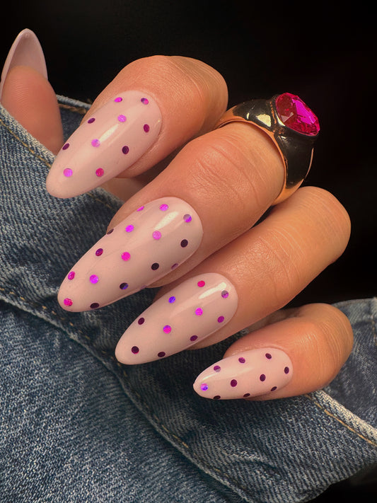 Nails with pink polka dot design on a denim background