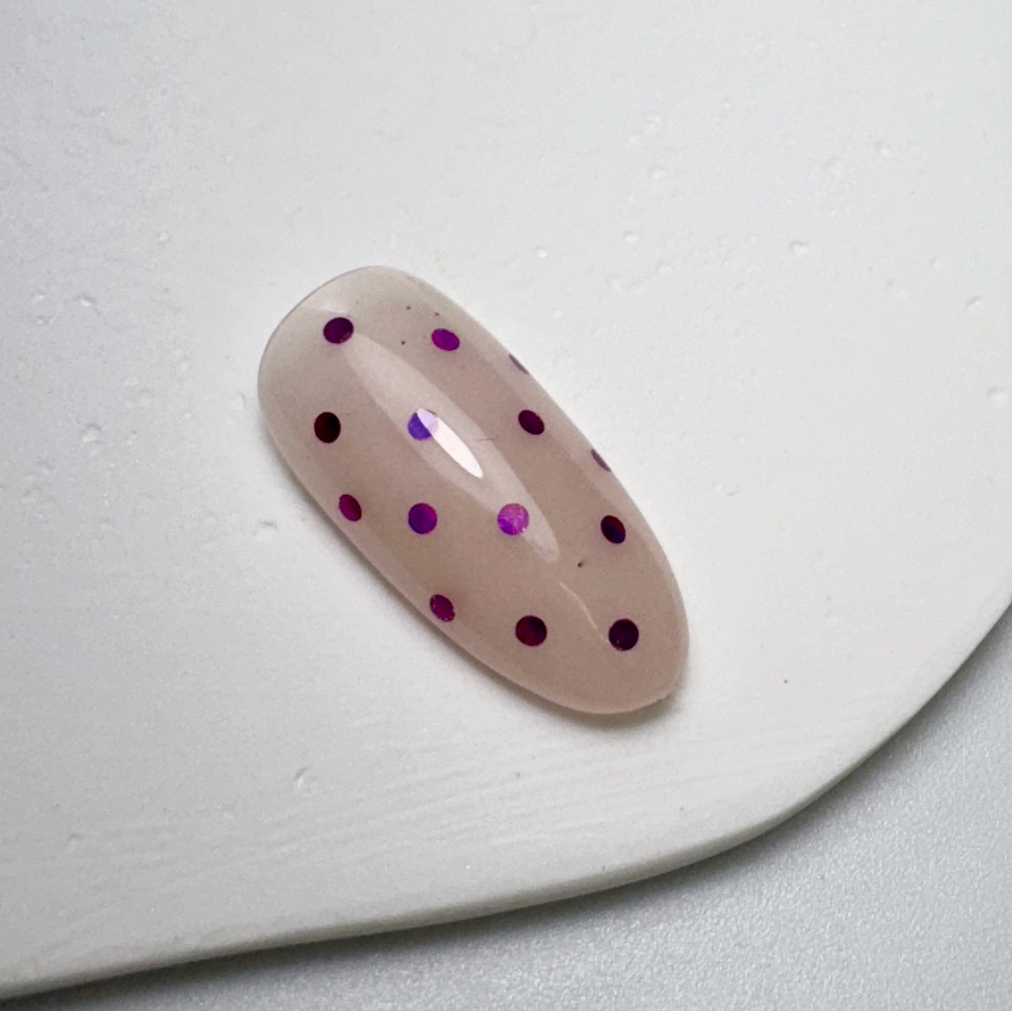 Decorated nail tip on white textured surface.
