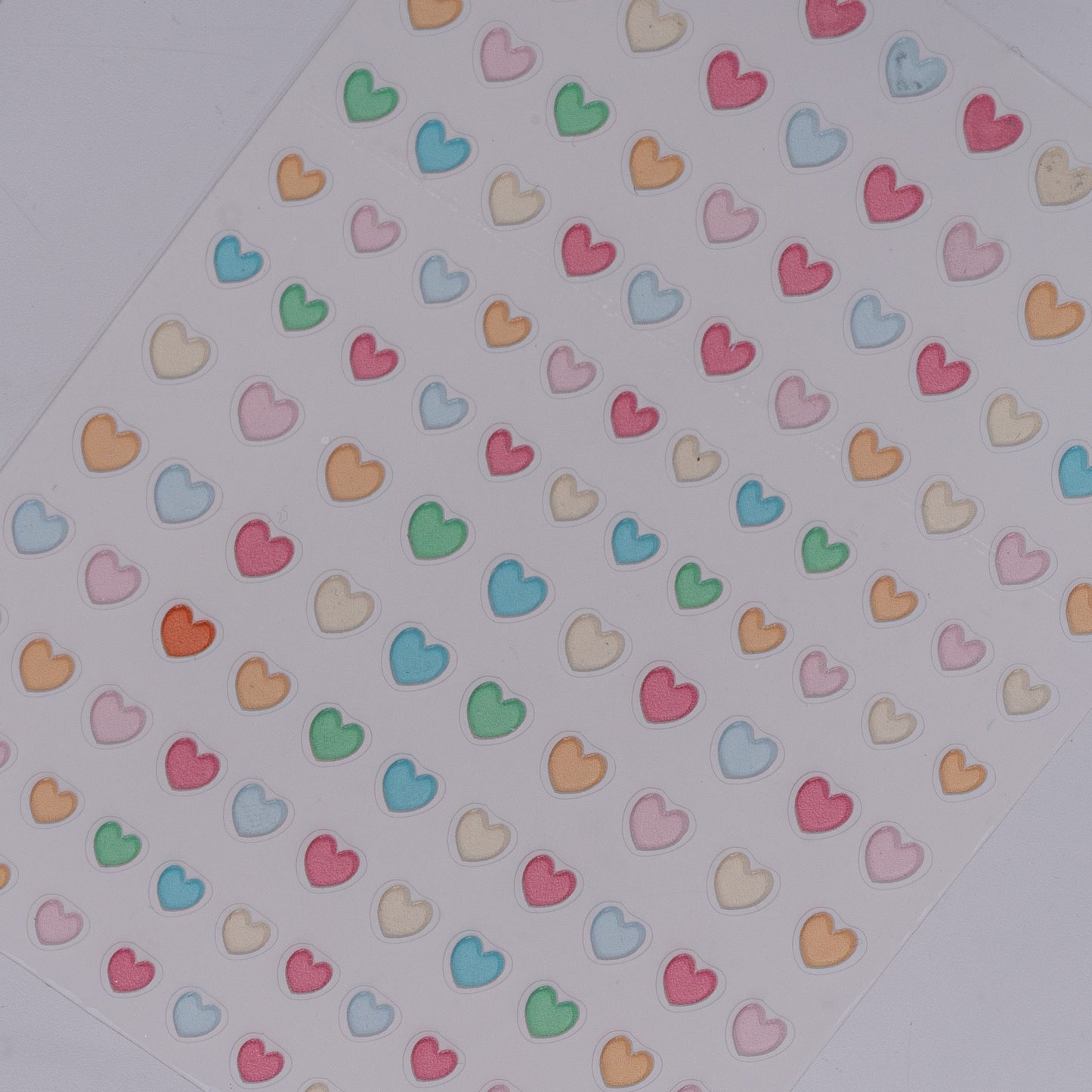 Sheet of colorful heart-shaped stickers on a white background