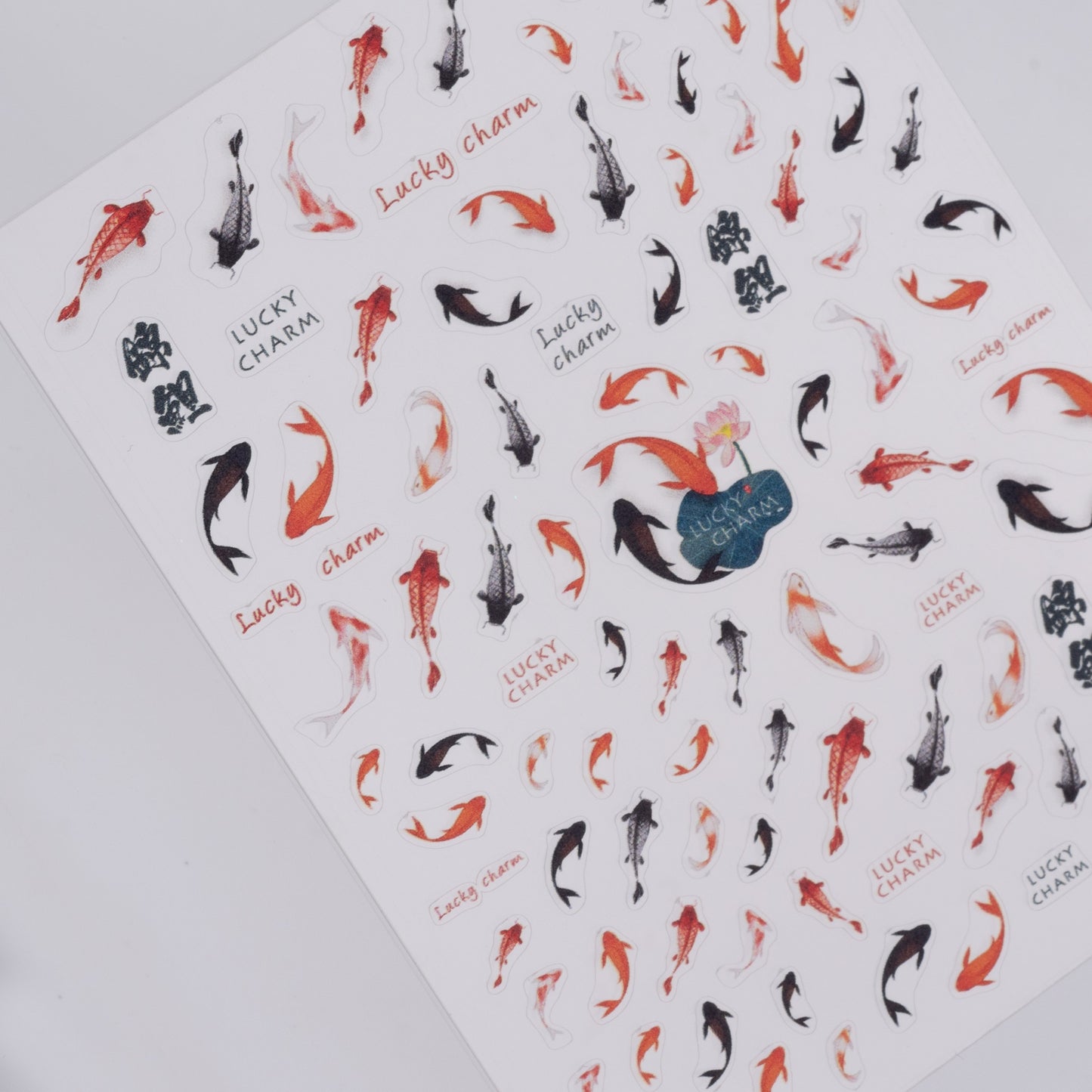Sheet of nail stickers with koi fish designs and 'Lucky Charm' text on a white background.