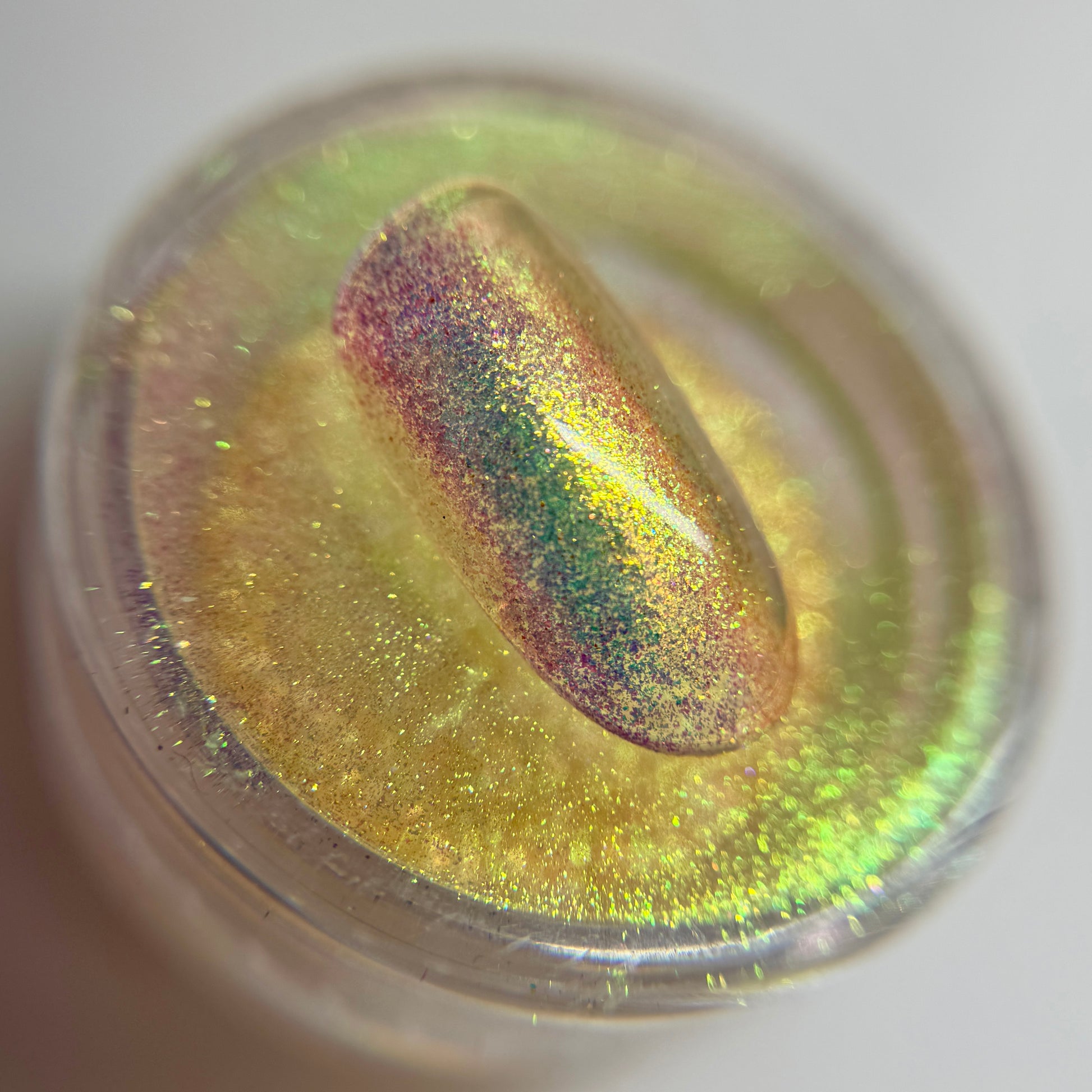 close up of iridescent colored bail tip resting on transparent jar on blurred background