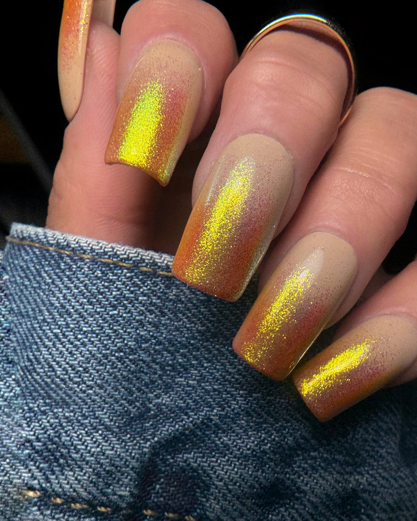 Nails with a gradient design of orange to yellow on a denim background