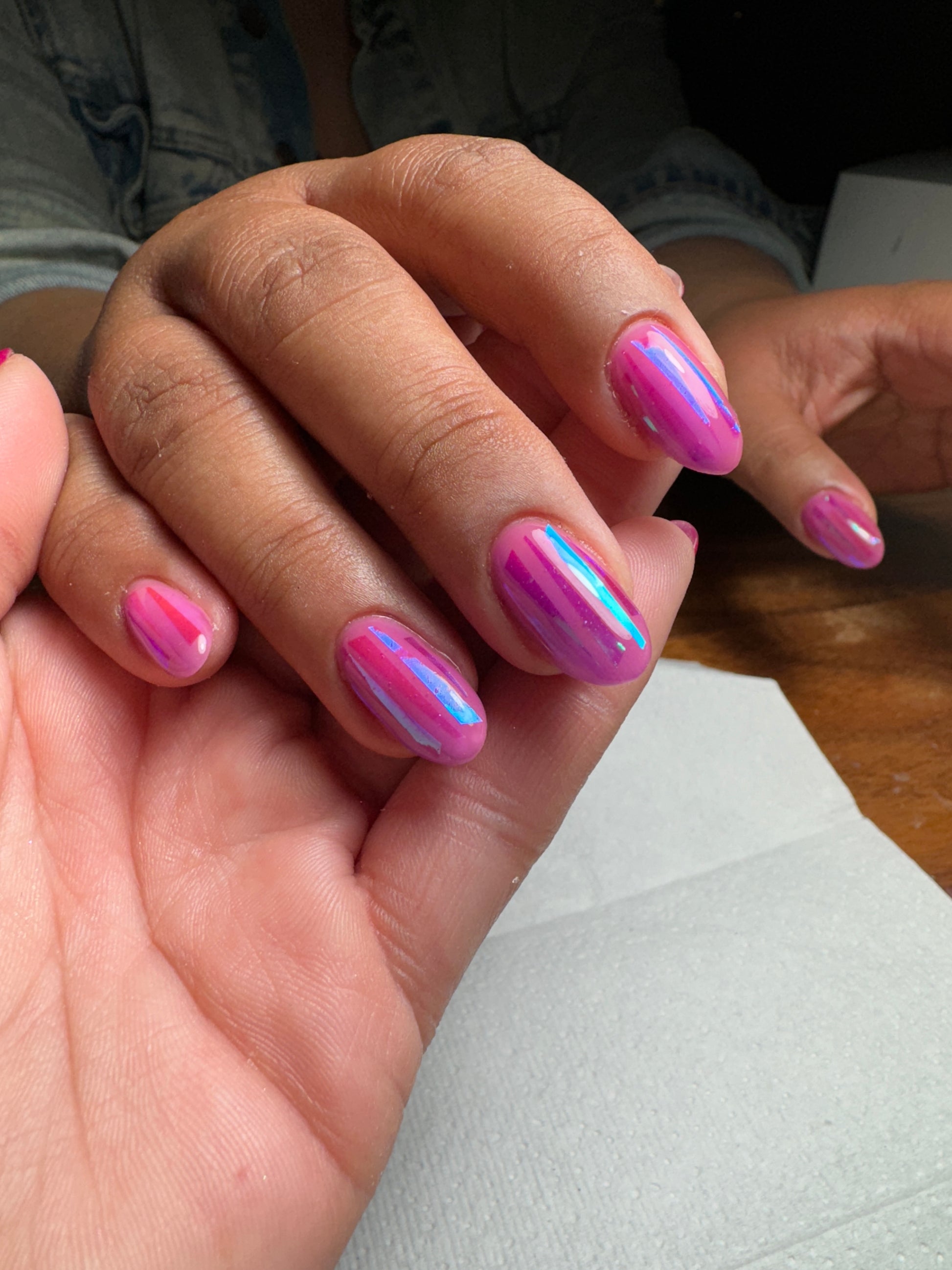 Manicured hand with pink design being held by an additional hand 