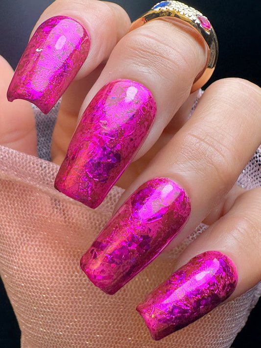 Close-up of a hand with pink glittery nail design on a neutral background