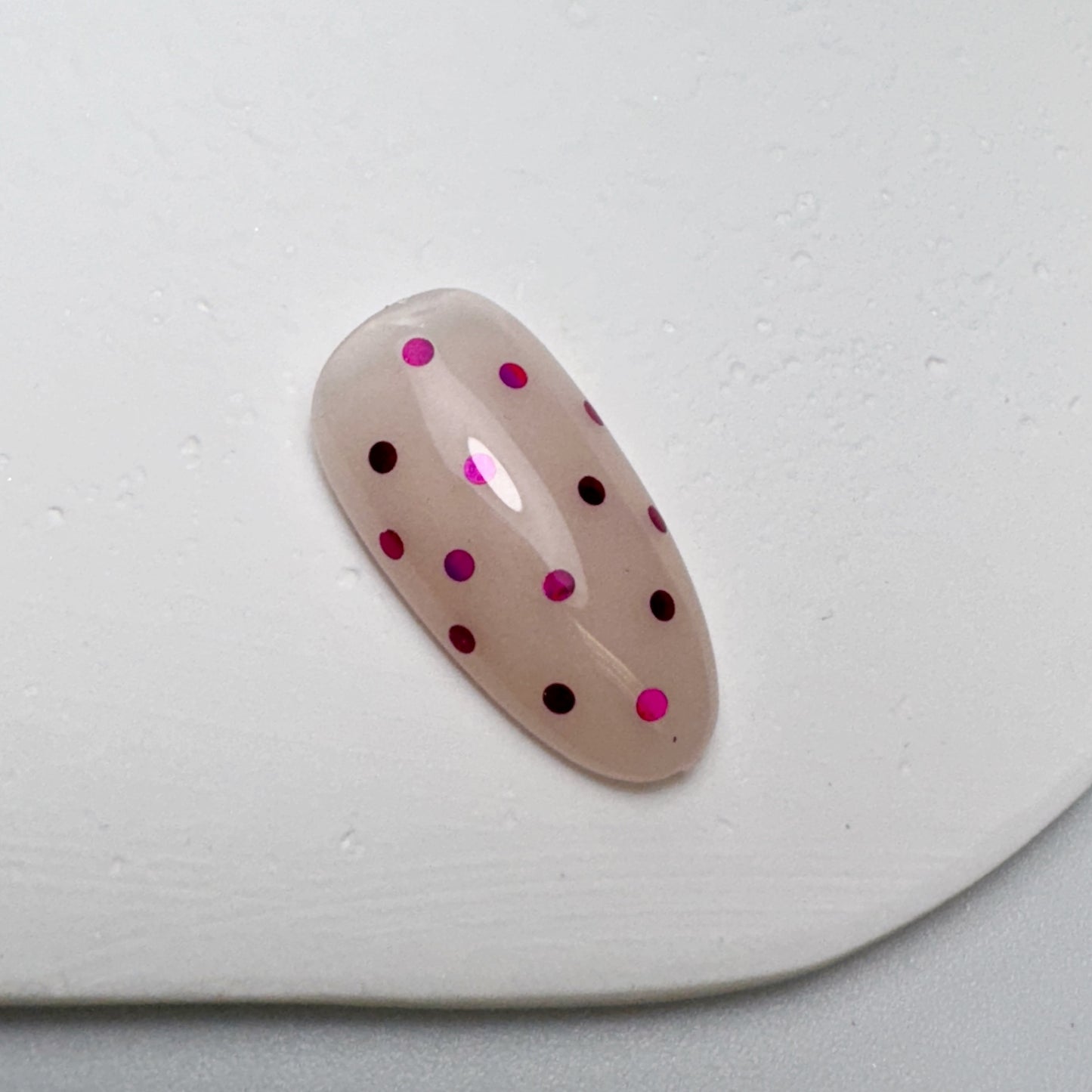 Decorated nail tip on white textured surface.
