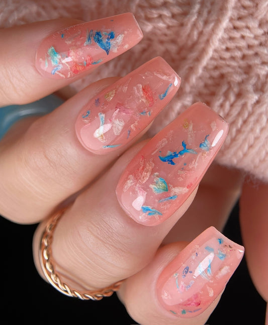 Peach-colored nails with floral designs on a textured background