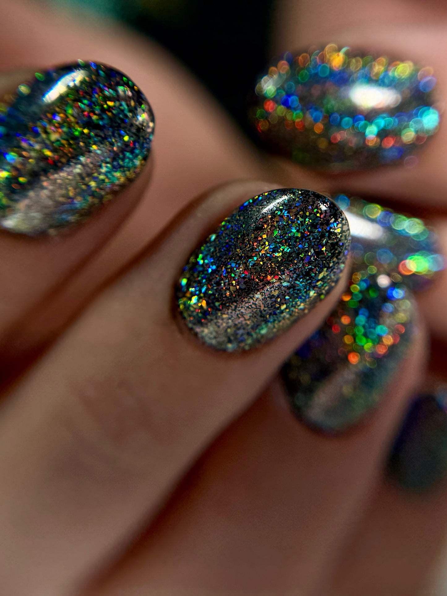 Close-up of a hand with glittery, multicolored nail  color.