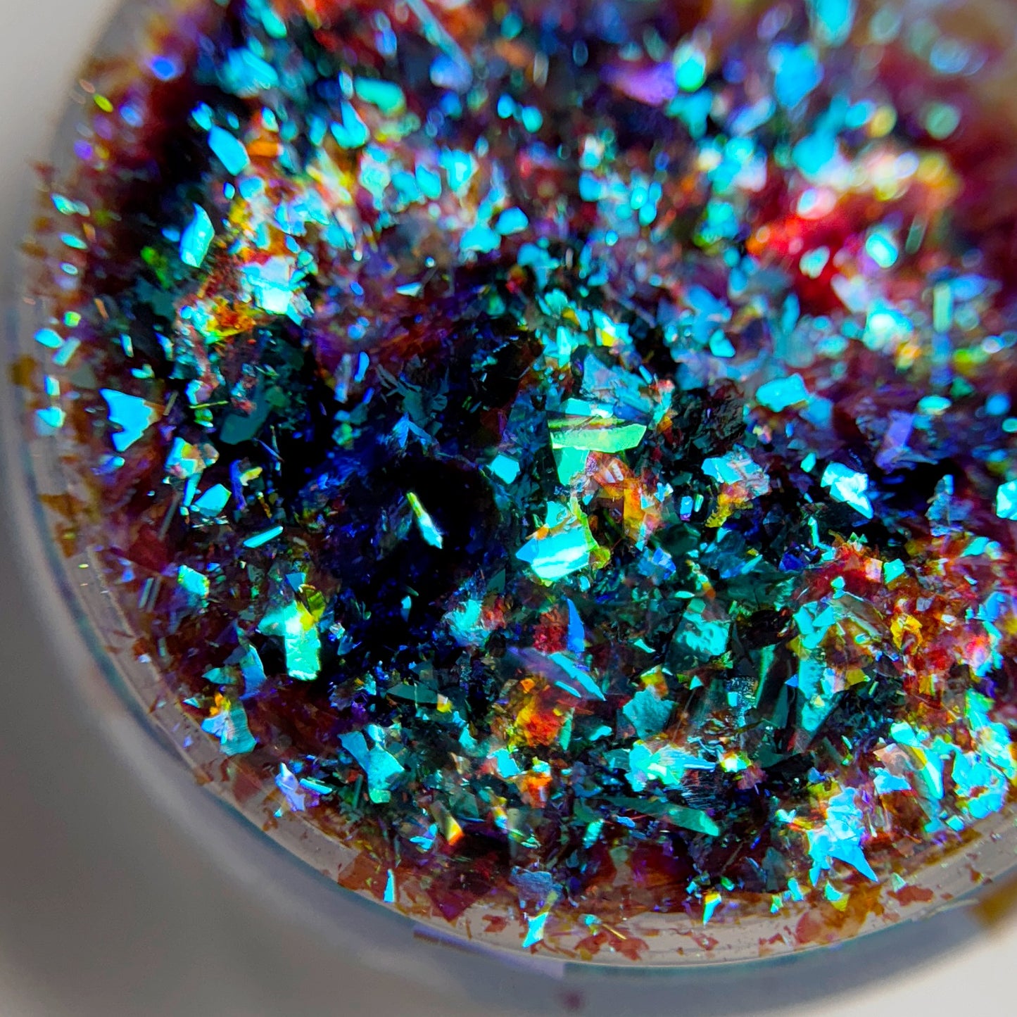 Close up of iridescent flakes in transparent jar on blurred background