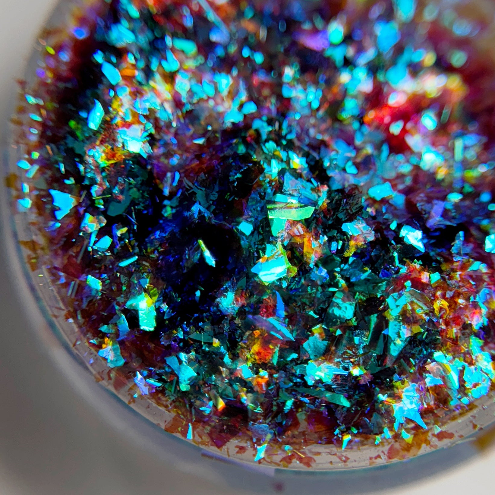 Close up of iridescent flakes in transparent jar on blurred background