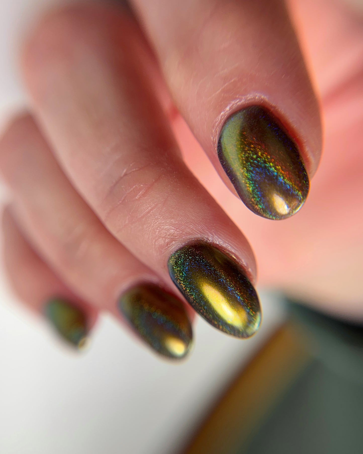 Close-up of a hand with iridescent nail color on a blurred background