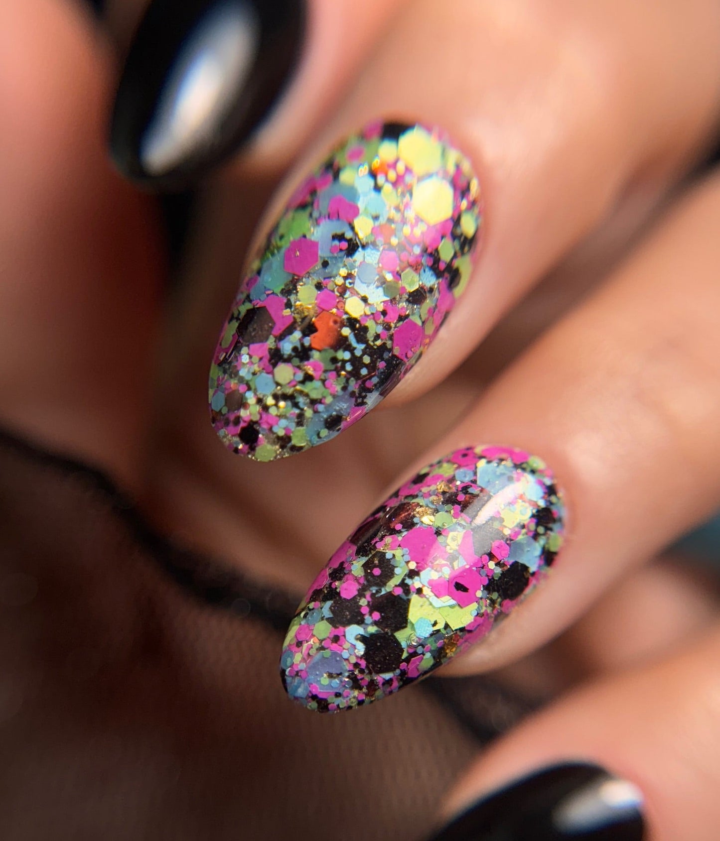 Nails with multicolored confetti design and black polish on a blurred background