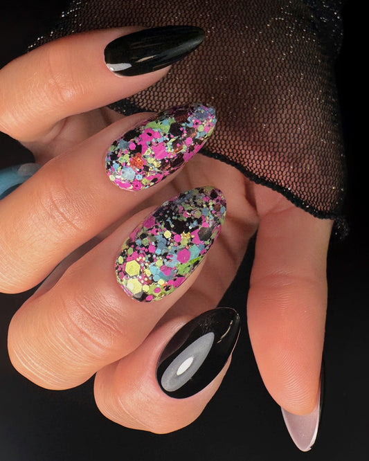 Close-up of a hand with black and multicolored polka dot nail design on a dark background